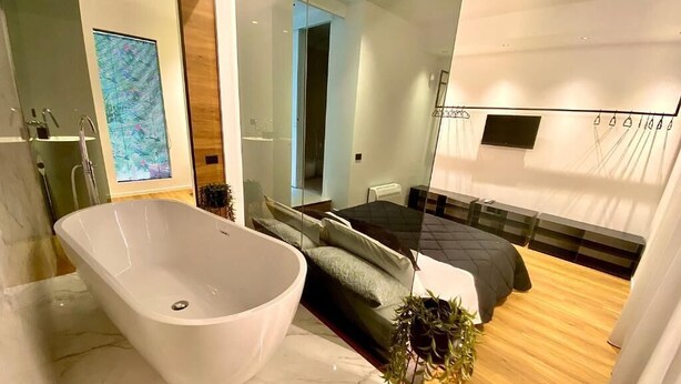 A modern bathroom with a freestanding bathtub, a large mirror, and a glass shower enclosure. - Exclusive suite in the historic center of Catania, private entrance (Catania)
