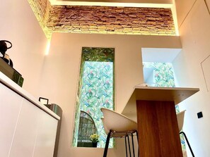 A modern kitchen with a stone accent wall, a window with a floral pattern, and a wooden counter. - Suite Mark – Exclusive Suite in the Heart of Catania's Historic Center (Catania)