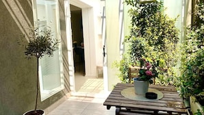 A patio with a wooden table and chairs, surrounded by potted plants and a small hanging plant. - Exclusive suite in the historic center of Catania, private entrance (Catania)