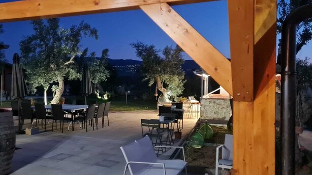 An outdoor patio area with a wooden pergola, tables, chairs, and a stone fireplace. - A village that preserves memory. A place to inhabit, not just to visit. (Cosenza)