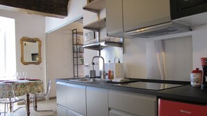 Una cocina con un lavamanos, un refrigerador rojo y una zona de comedor con una mesa y sillas.
