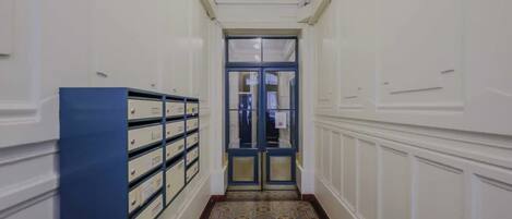 A hallway with a patterned carpet, a blue storage unit, and a double door at the end.