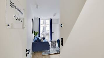 A modern living room with a blue sofa, a small side table, and a large window with blue curtains.