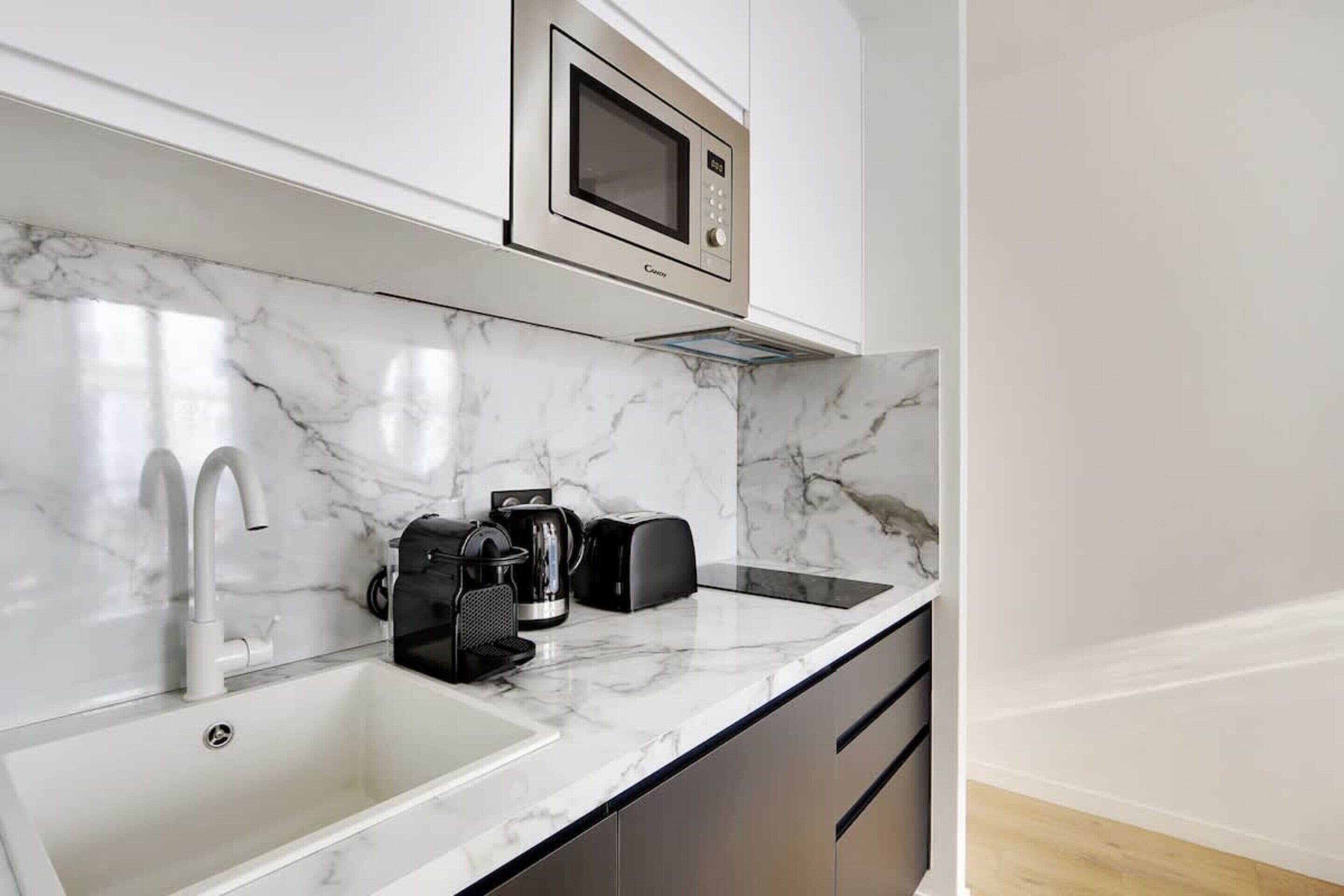A modern kitchen with a built-in microwave, a sink, and a coffee maker.