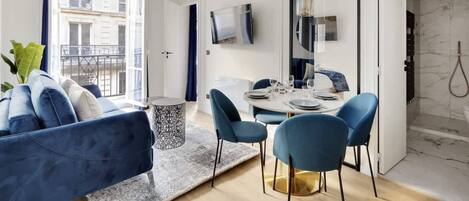 Ein modernes Wohnzimmer mit einer Couch, einem Esstisch, Stühlen und einem Fernseher.