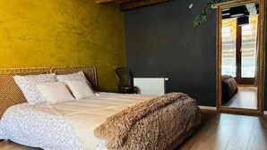 Een slaapkamer met een bed, een spiegel, een stoel en een raam.