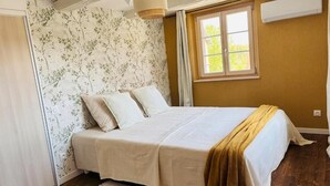 Een slaapkamer met een bed, een raam en een wand met bloemenbehang.