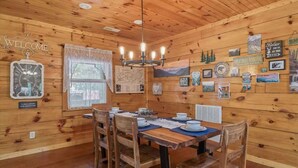 A wooden cabin interior with a dining table set for four, surrounded by wooden chairs.