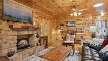 Ein gemütliches Blockhaus-Interieur mit Kamin aus Stein, Ledersofa und Holzmöbeln.