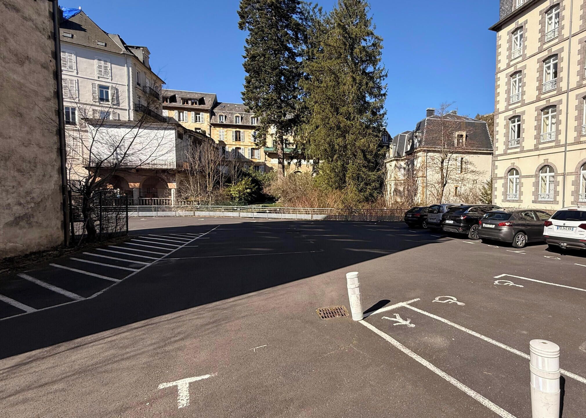 A parking lot with marked spaces, a pedestrian crossing, and buildings in the background.