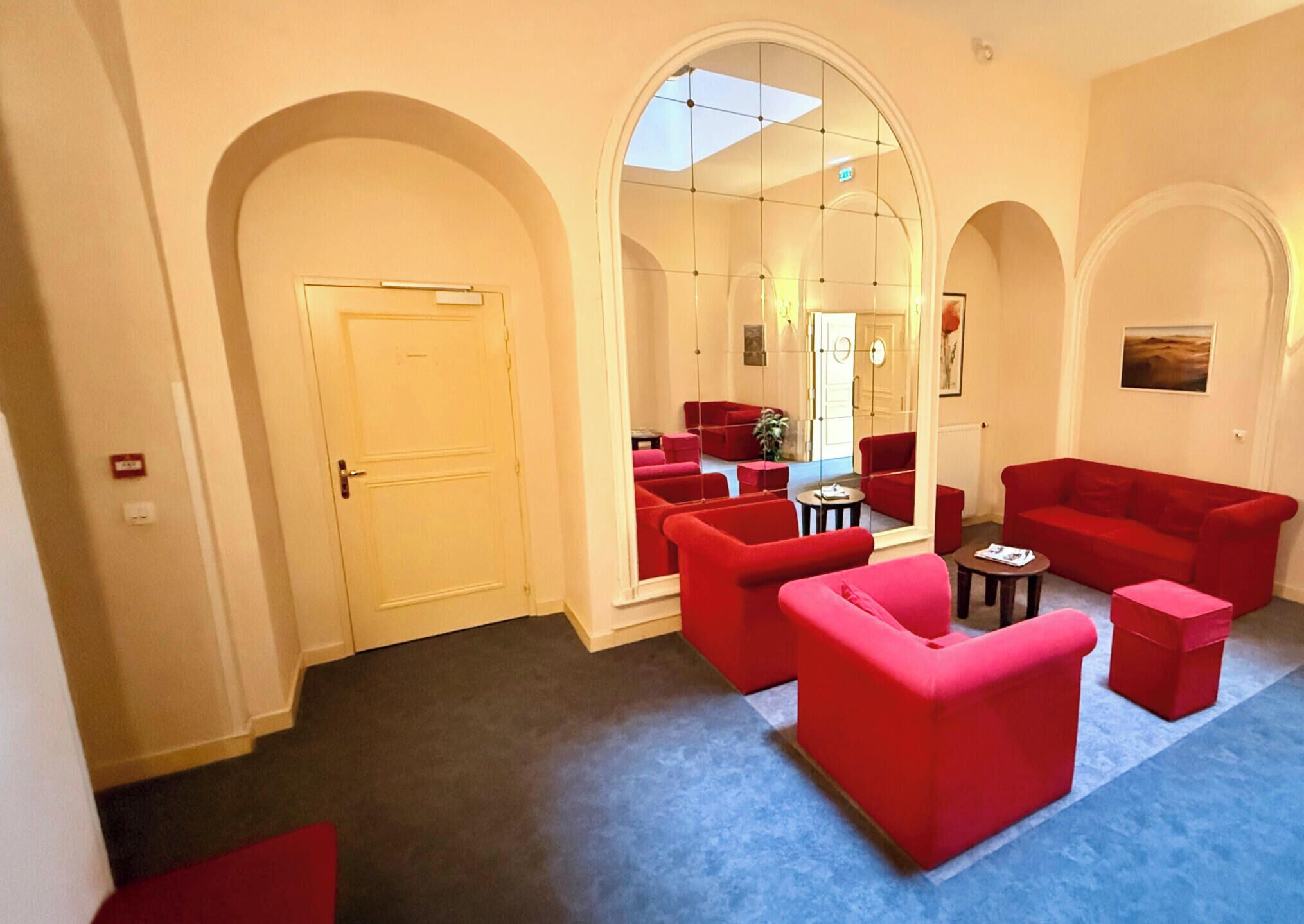 A hotel lobby with red sofas, a coffee table, and a door.