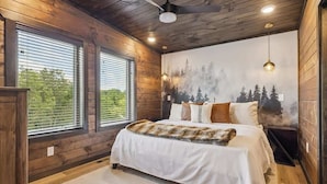 Une chambre avec un grand lit, des murs en bois et une fresque représentant des arbres.