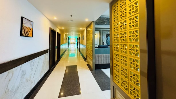 A hotel hallway with a marble floor, a reception desk, and a decorative yellow partition. - Col's Hotel Uphaar (Ujjain)