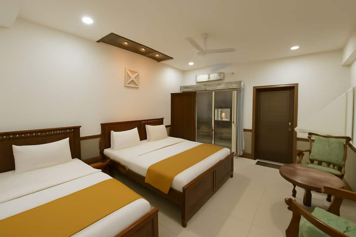 Une chambre d’hôtel avec deux lits, une armoire, une chaise et un ventilateur de plafond.