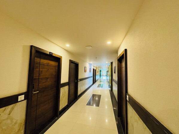 A hotel corridor with wooden doors, white tiled floors, and a long hallway.