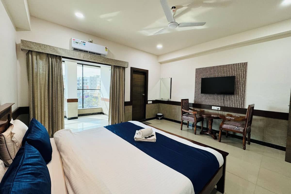 Une chambre d’hôtel avec un grand lit, un bureau avec des chaises, une télévision et un appareil de climatisation.