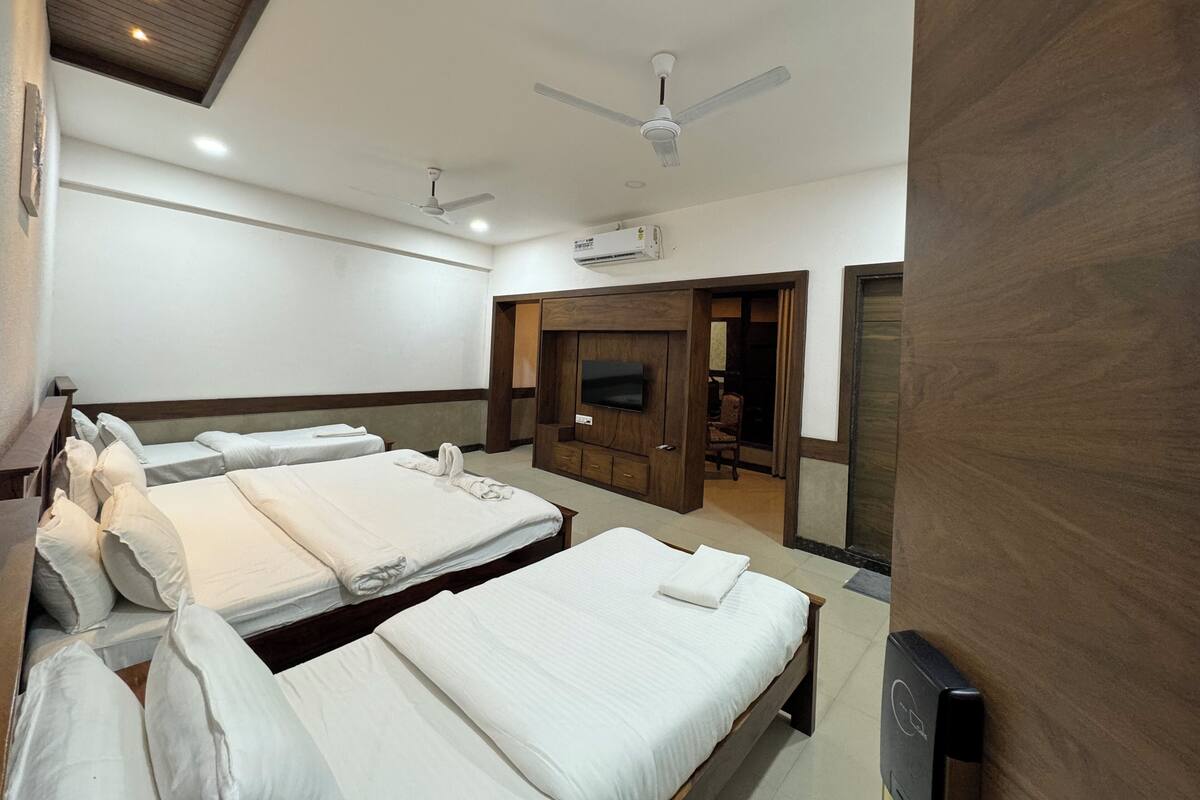 Une chambre d’hôtel avec deux lits, une télévision, un climatiseur et un ventilateur de plafond.