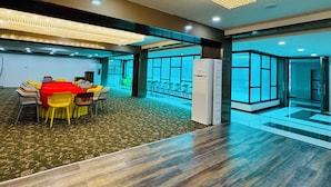 A conference room with a long table, chairs, and a modern chandelier. - Col's Hotel Uphaar (Ujjain)