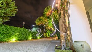 A nighttime outdoor area with a gravel path, greenery, and a decorative light installation. - Villa Yucca - B&B and Glamping (Torano Nuovo)