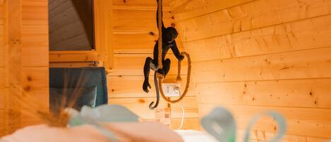 Ein Holzblockhaus-Interieur mit einer Hänge-Seil, einem Fenster und einem Bett mit aufgerollten Handtüchern.