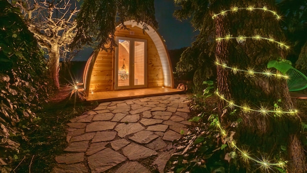 A wooden cabin with a stone pathway leading to a door, surrounded by trees and illuminated by string lights. - Villa Yucca - B&B and Glamping (Torano Nuovo)
