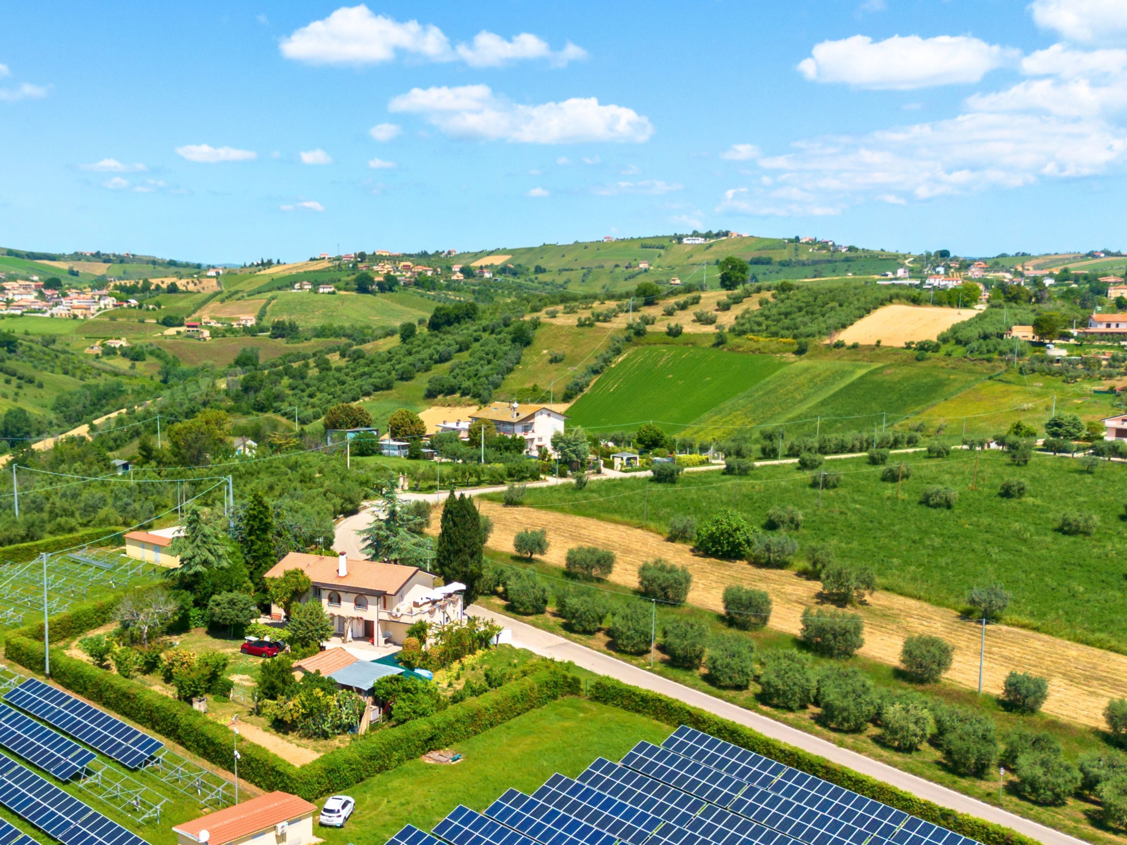 Ländliche Landschaft mit Häusern, Solaranlagen und sanften Hügeln.