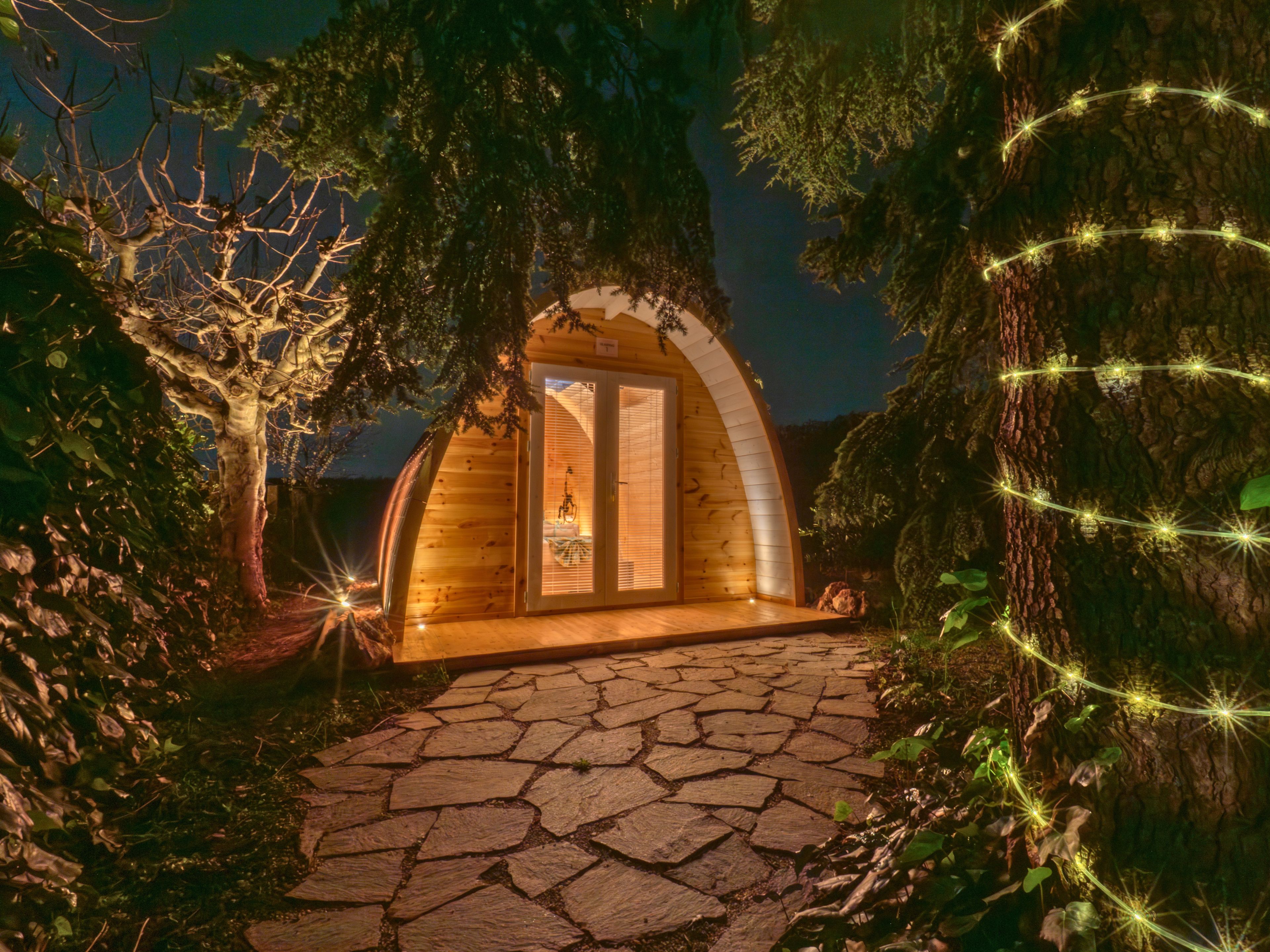 Una cabaña de madera con un sendero de piedra que lleva a ella, rodeada de árboles y follaje.