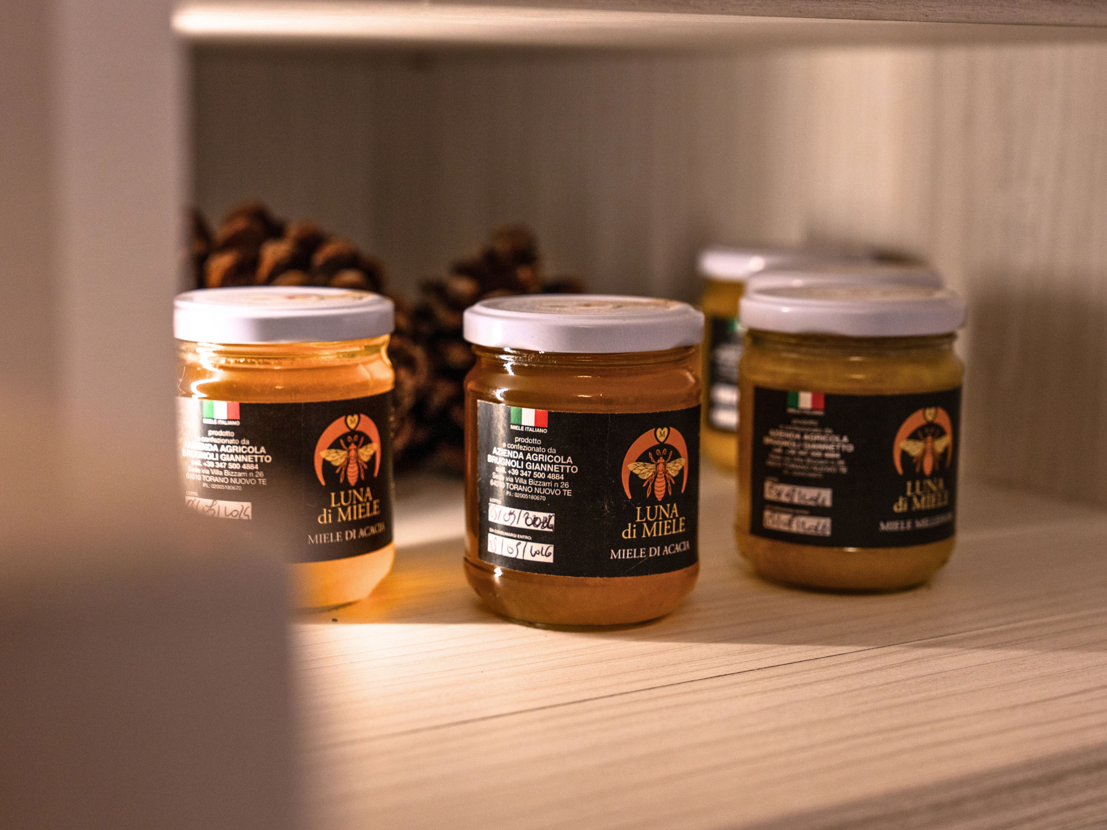 Trois pots de miel sont posés sur une étagère.