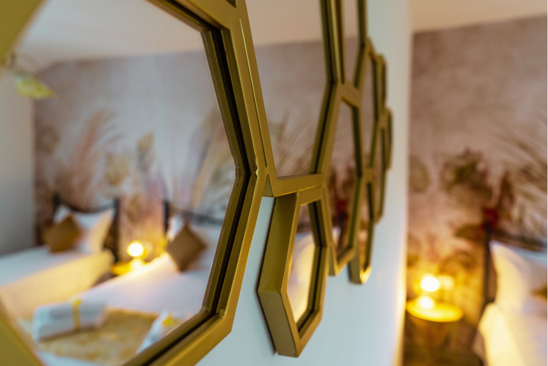 Um quarto com decoração geométrica na parede, uma cama com almofadas e um quadro na parede.
