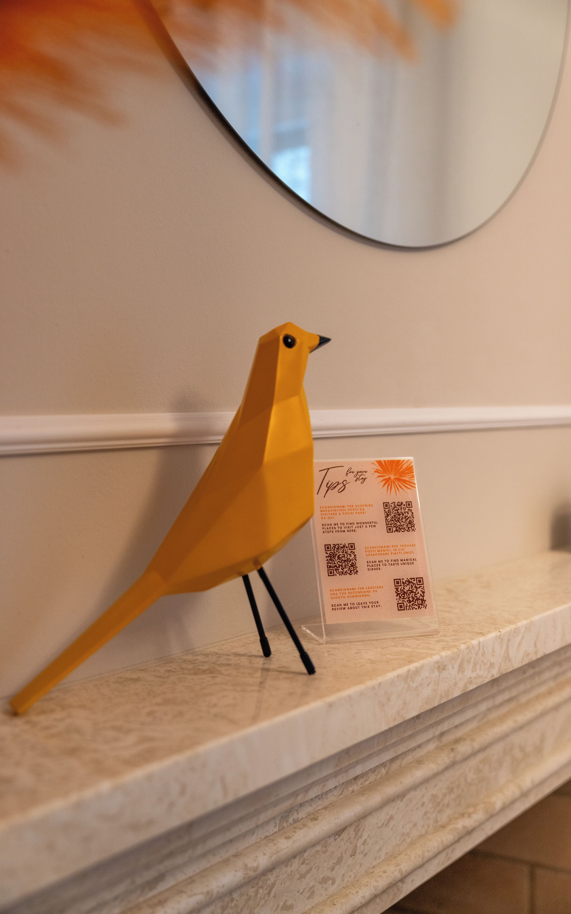 A yellow bird figurine on a marble shelf next to a QR code for a restaurant.