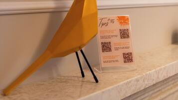 A yellow bird figurine on a marble shelf next to a QR code for a restaurant.