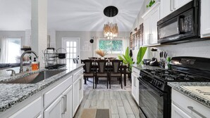 A modern kitchen with granite countertops, a black stove, and white cabinetry.