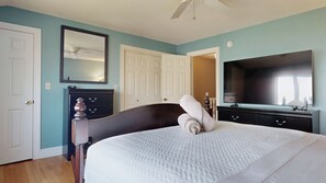 Ein Schlafzimmer mit Bett, Kommode, Fernseher und einer Tür.