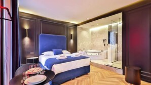 Une chambre d’hôtel moderne dotée d’un grand lit, d’une douche en verre et d’un coin repas avec une table mise pour deux personnes.