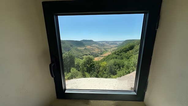 Une fenêtre donnant sur un paysage vallonné.