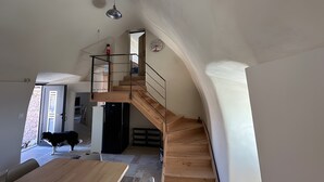 Un intérieur moderne avec un escalier en bois, un coin repas et un chien.