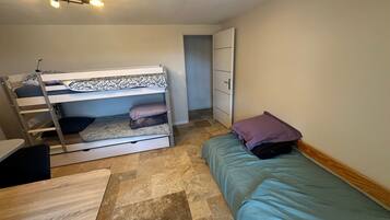 A bunk bed with a desk and chair, a single bed with a pillow, and a wardrobe.