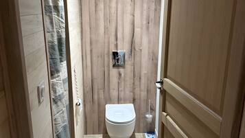 A bathroom with a wooden wall, a toilet, and a shower curtain.