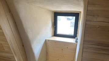 A room with a sloped ceiling, a small window, and a wooden floor.