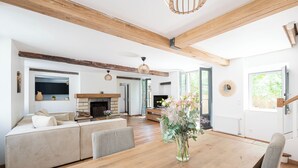 A spacious living area with a wooden dining table, a sofa, and a fireplace. - Beautiful family house sleeps 9 near the castle in Dampierre (Dampierre-en-Yvelines)