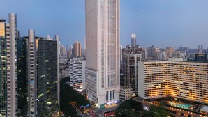 A high-rise building with a modern glass facade, surrounded by other tall buildings in an urban setting. - GWEN JANE Hotel - Guangzhou Yuexiu Taojin Metro Station Branch (Guangzhou)