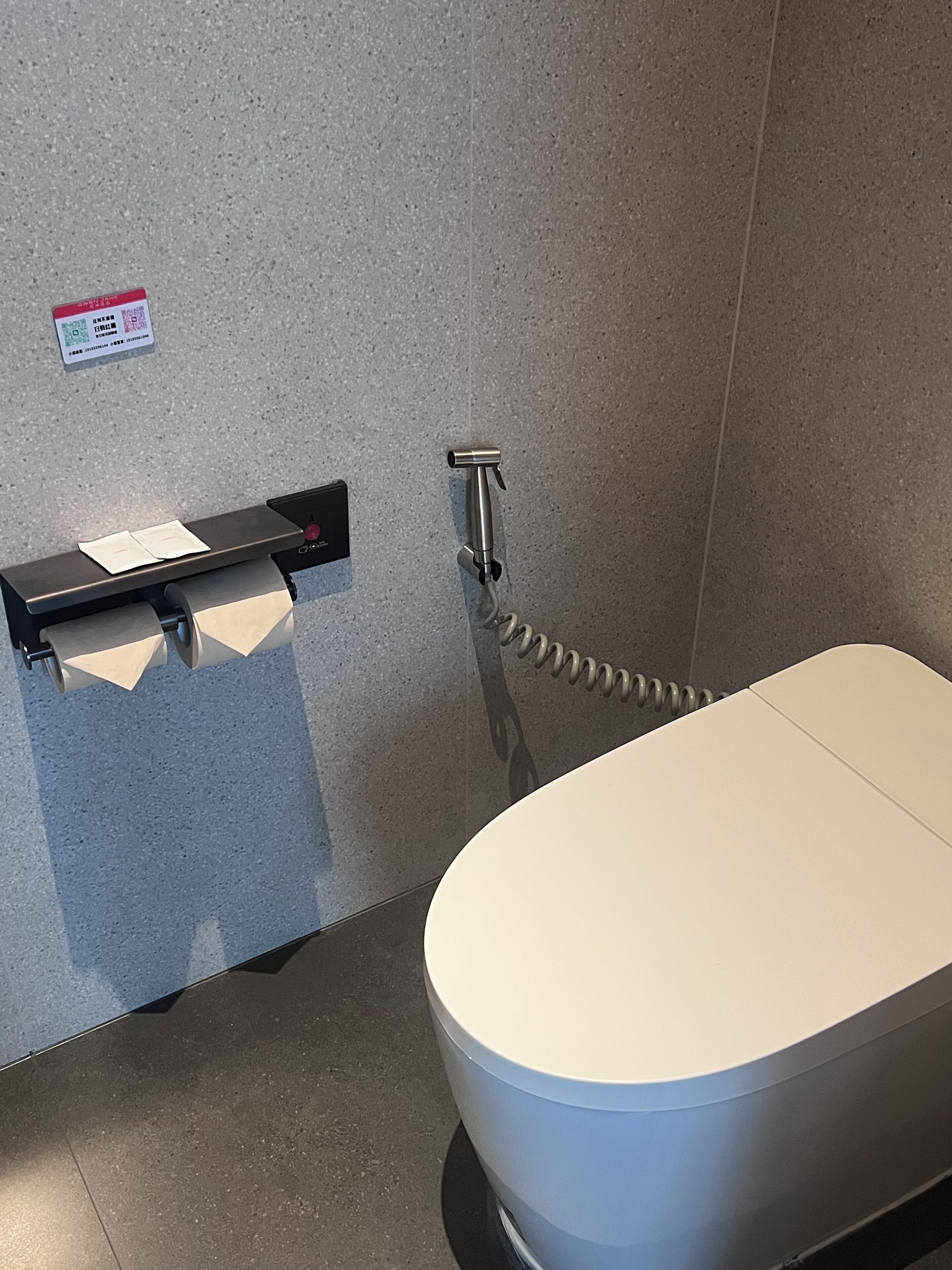 A bathroom with a toilet, a paper towel dispenser, and a hand dryer.