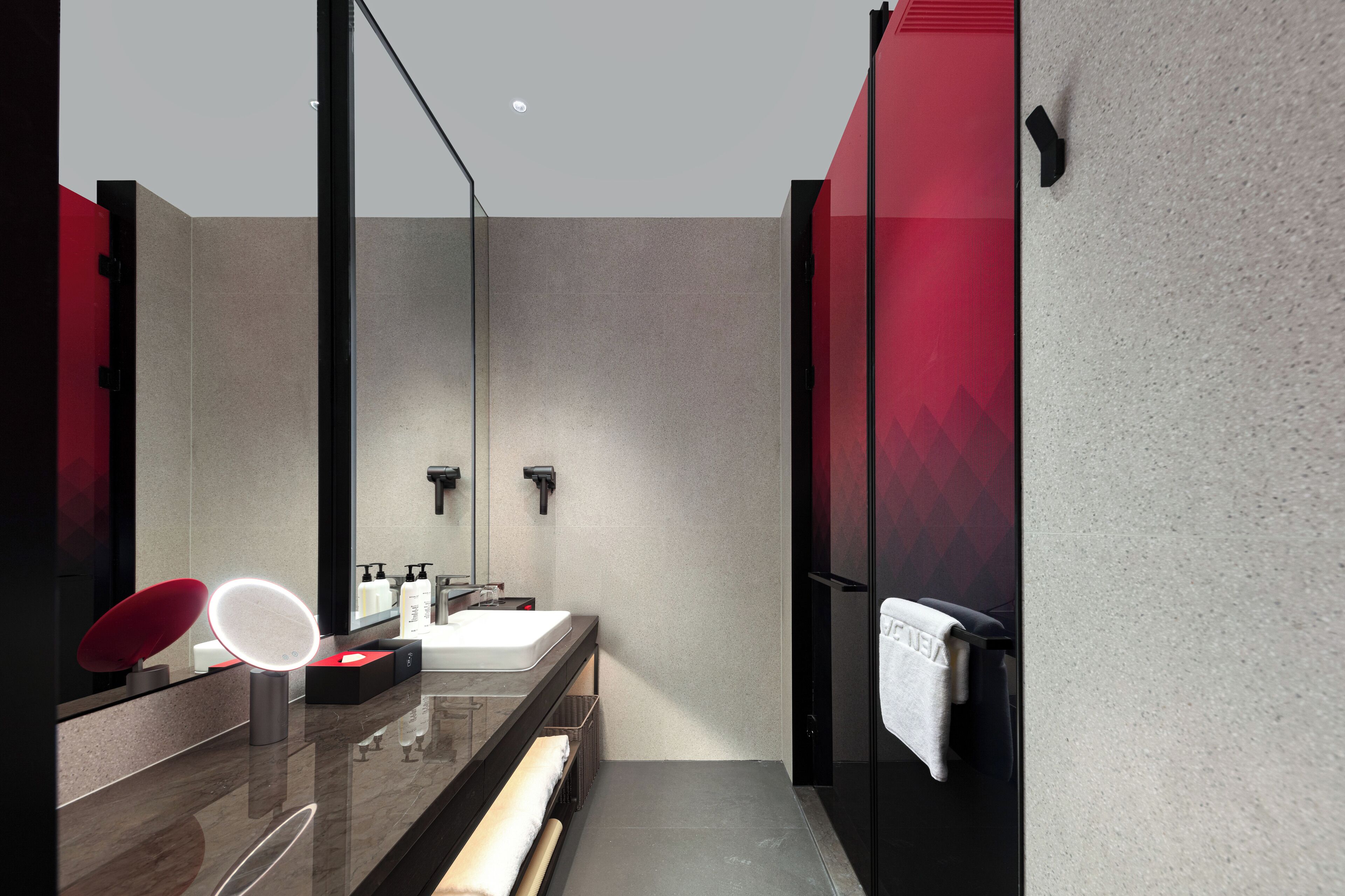 A modern bathroom with a large mirror, a sink, and a towel rack.