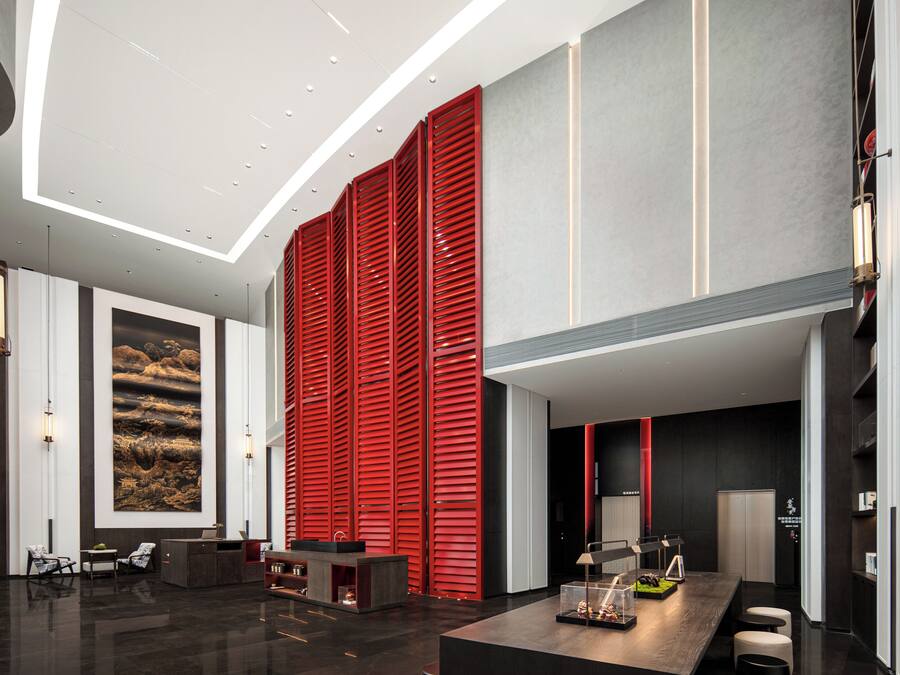 Um lobby moderno com um balcão de recepção, área de estar e uma grande pintura abstrata na parede.