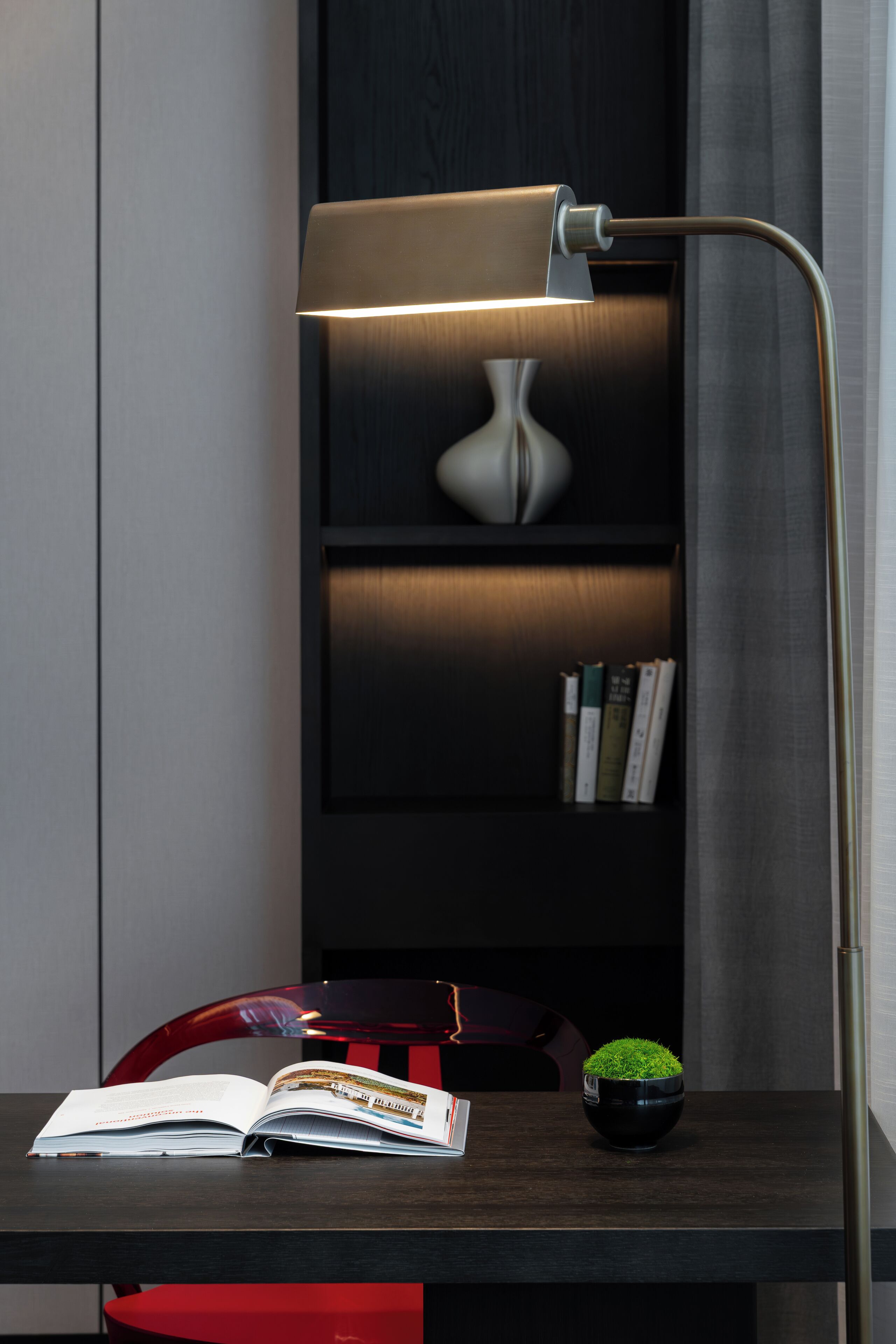 A desk with a lamp, a book, and a small potted plant.