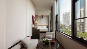 A modern hotel room with a large window, a sofa, a small table with a vase, and a bed. - GWEN JANE Hotel - Guangzhou Yuexiu Taojin Metro Station Branch (Guangzhou)