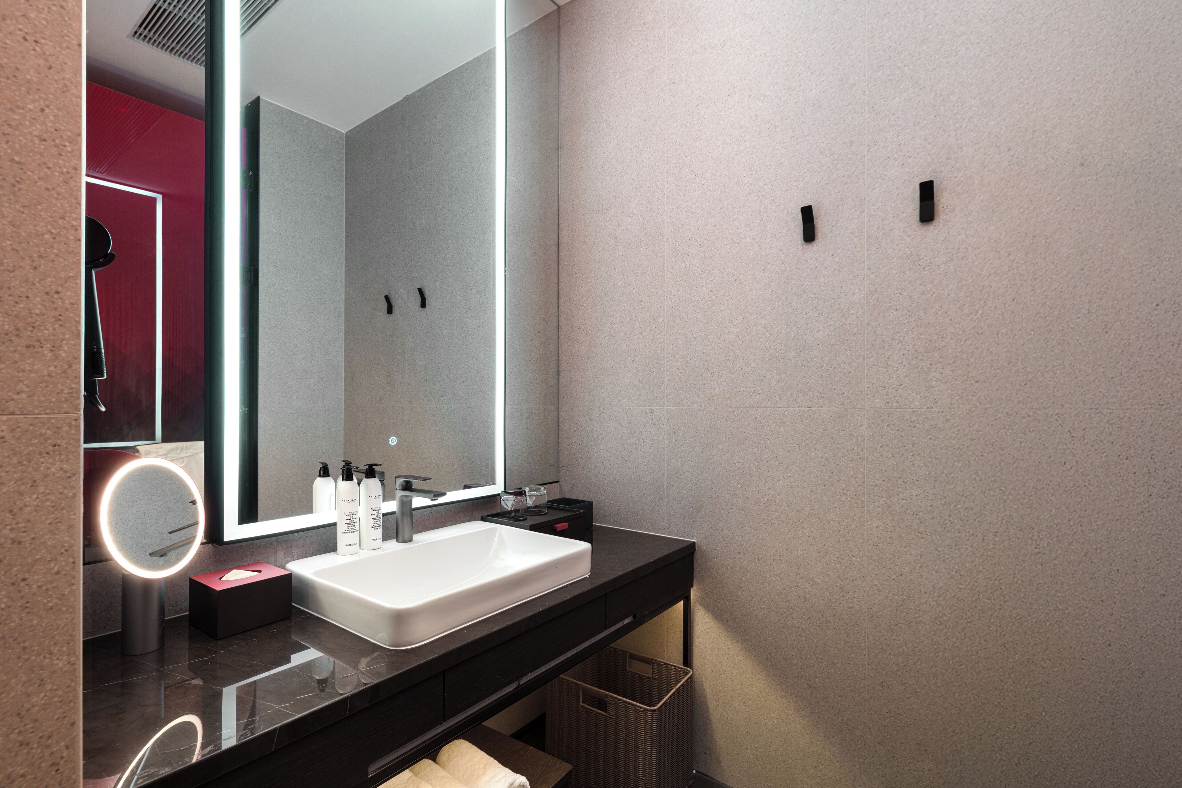 A modern bathroom with a large mirror, white sink, and black countertop.