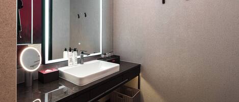 A modern bathroom with a large mirror, white sink, and black countertop.