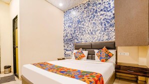 A hotel room with a large bed, a patterned wall, and a nightstand. - Hotel Priceless (Mumbai)