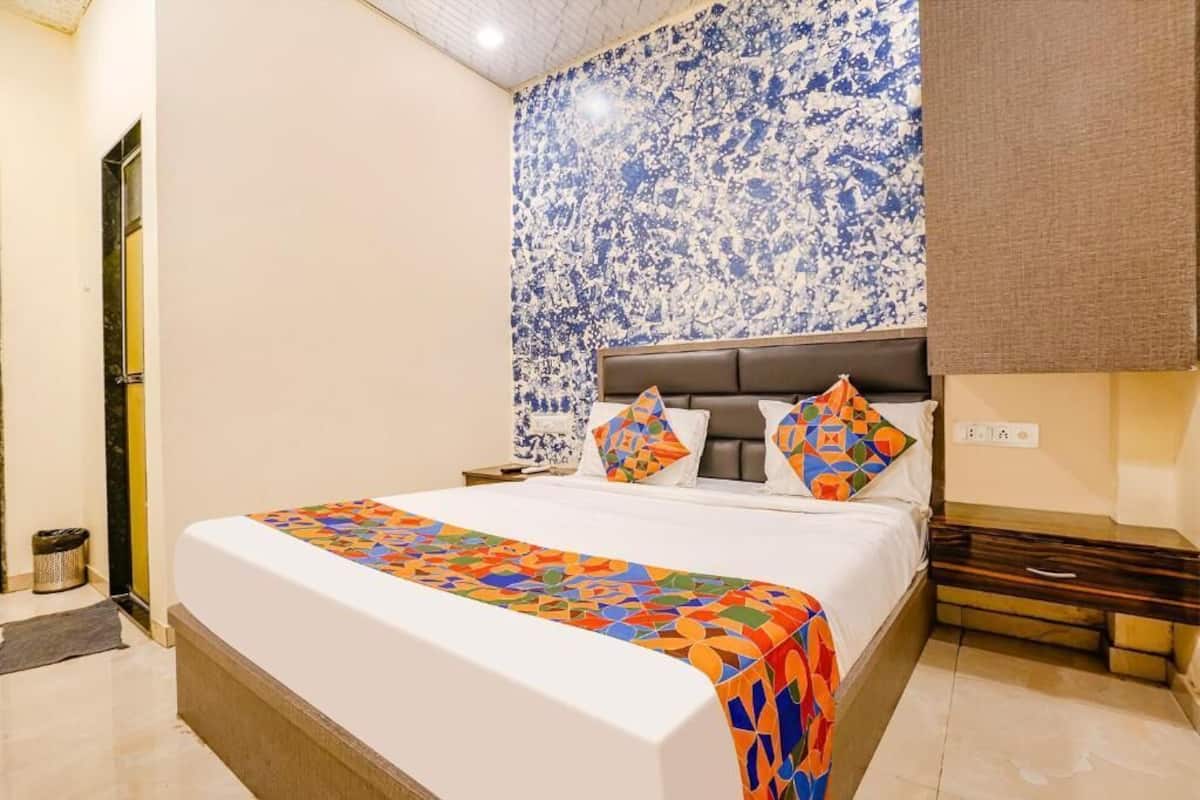A hotel room with a large bed, a patterned wall, and a nightstand.